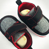 Red, black and grey baby shoes with name label